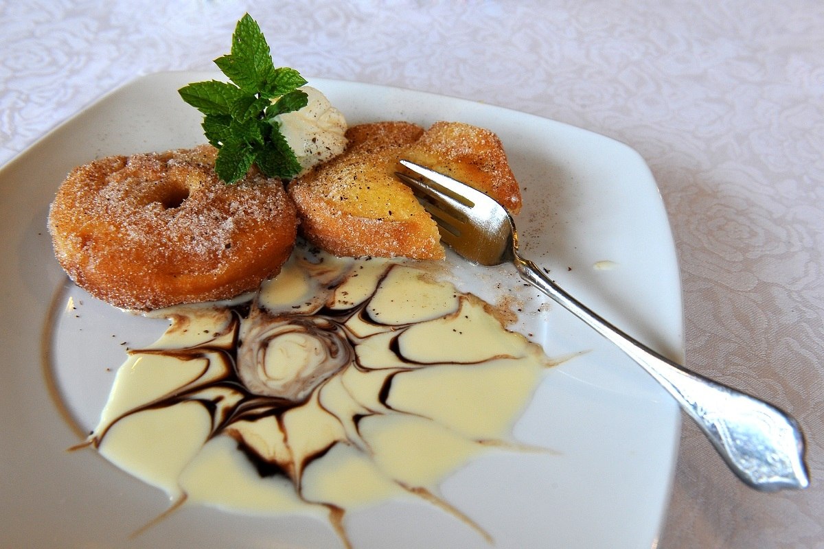 Ein Apfelküchle mit Zimt, Zucker und Vanillesauce auf einem Teller
