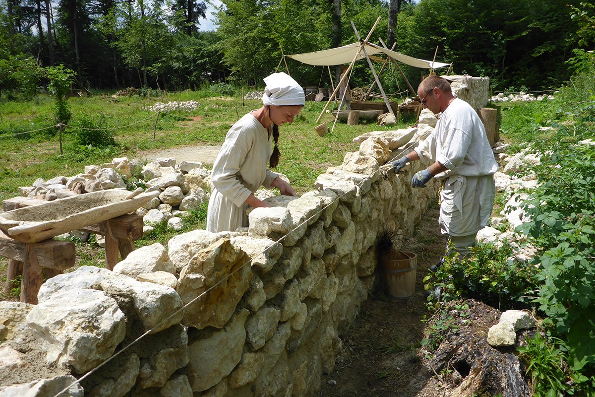 Zwei Arbeiter erstellen die Steinmauer, die den Obstgarten der zukünftigen Klosteranlage Campus Galli in Meßkirch schützen soll
