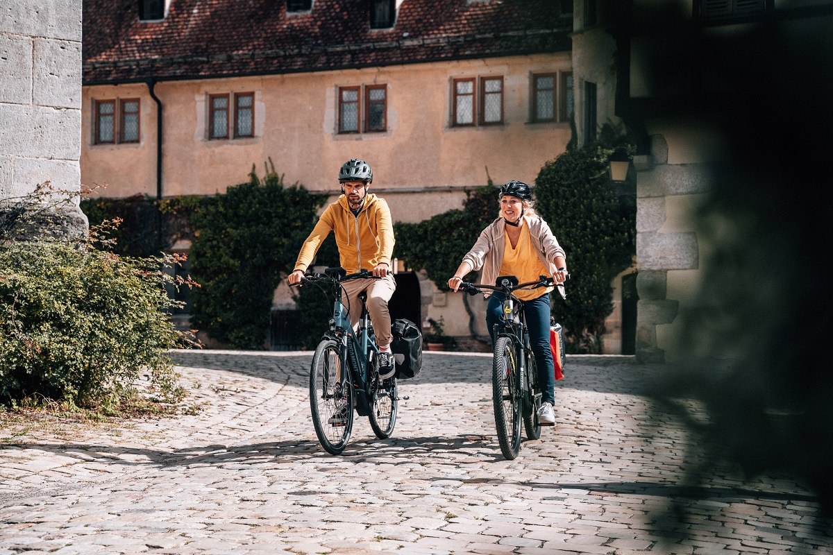 Zwei Radfahrer fahren durch den Innenhof des Kloster und Schloss Bebenhausen bei Tübingen.