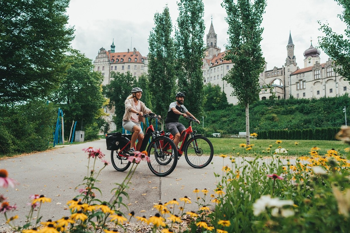 Fahrradfahrer fahren vor dem Hohenzollernschloss Sigmaringen entlang